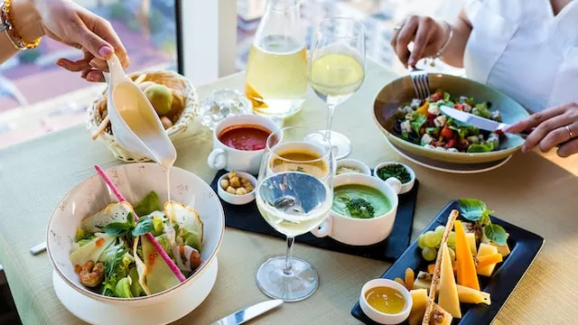 This promotional image showcases a delicious bowl of vegetable salad presented on a pristine white ceramic plate, accompanied by a sparkling wine glass. It is designed to entice visitors to explore the vibrant city of Houston and all that it has to offer.